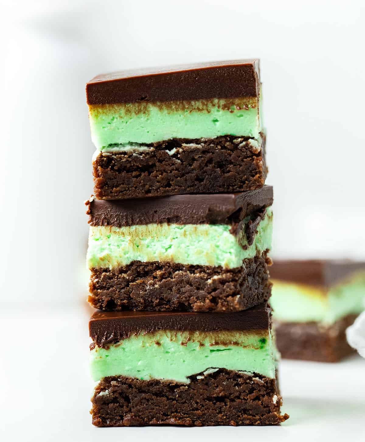 Stack of Fudgy Chocolate Mint Brownies on a white table.