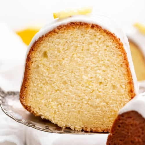 Piece of Lemon Pound Cake being lifted up by a cake server from a platter.