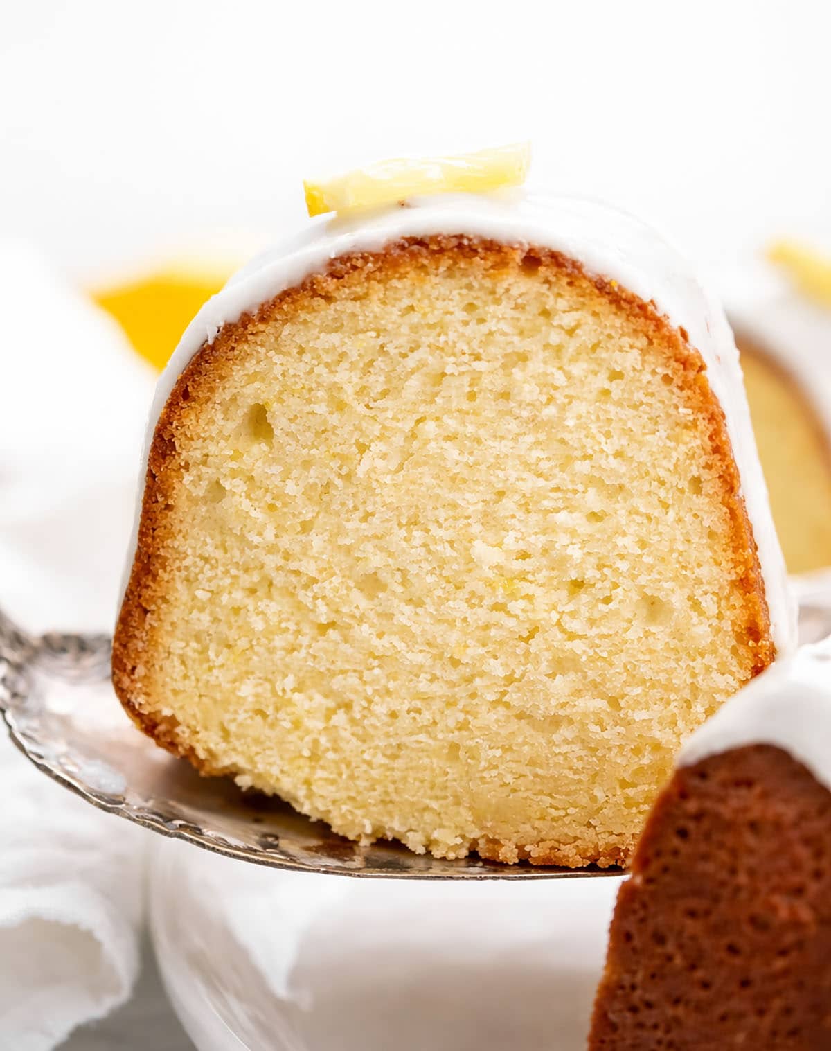 Piece of Lemon Pound Cake being lifted up by a cake server from a platter.