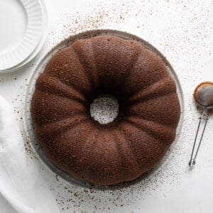 Whole Chocolate Pound Cake on a White Cake Plate on a Table.