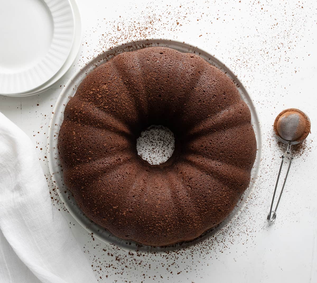 Whole Chocolate Pound Cake on a White Cake Plate on a Table.