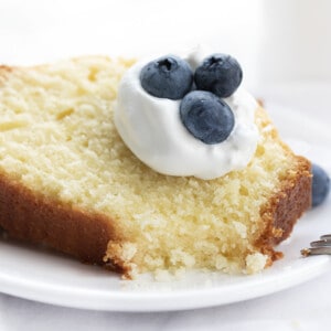 Vanilla Pound Cake on a Plate with Whipped Cream and Blueberries and a Bite Removed Showing Inside. Dessert, Cake, Pound Cake, Vanilla Pound Cake, Loaf Cake, Loaf Pound Cake, Vanilla Cake, Old Fashioned Cake Recipes, Original Vanilla Pound Cake, No Vanilla Extract Cake, recipes, iambaker, i am baker