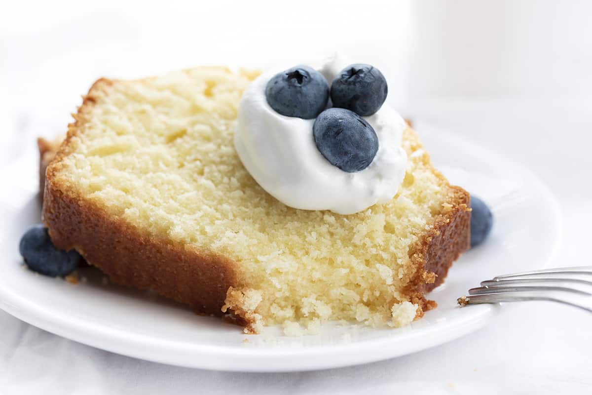 Vanilla Pound Cake on a Plate with Whipped Cream and Blueberries and a Bite Removed Showing Inside. Dessert, Cake, Pound Cake, Vanilla Pound Cake, Loaf Cake, Loaf Pound Cake, Vanilla Cake, Old Fashioned Cake Recipes, Original Vanilla Pound Cake, No Vanilla Extract Cake, recipes, iambaker, i am baker