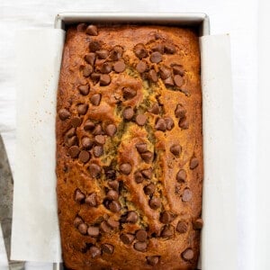 Loaf of Chocolate Chip Banana Bread on a White Counter with a Bread Knife.