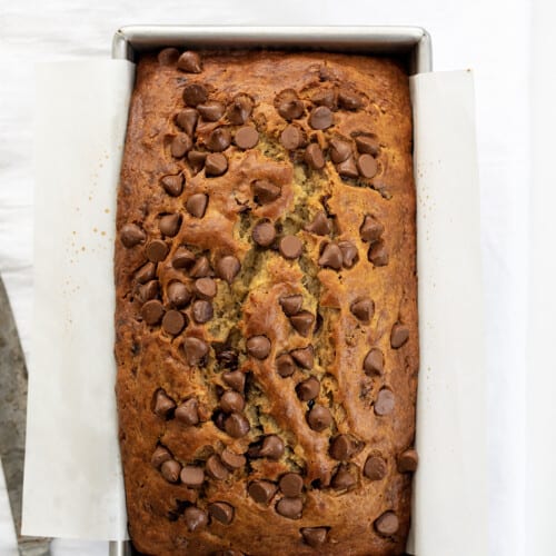 Loaf of Chocolate Chip Banana Bread on a White Counter with a Bread Knife.