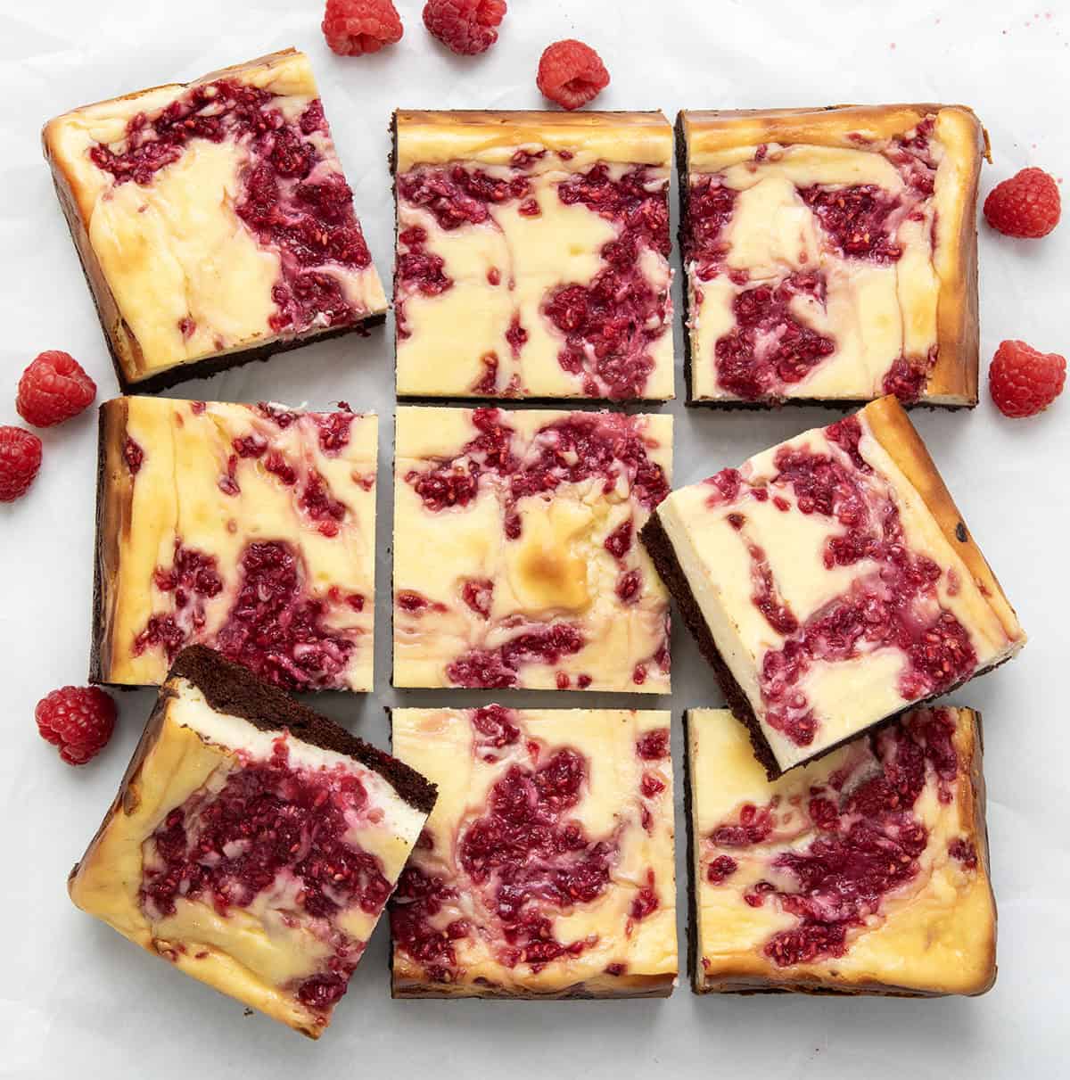 Cut up Raspberry Cheesecake Brownies on a white table from overhead.