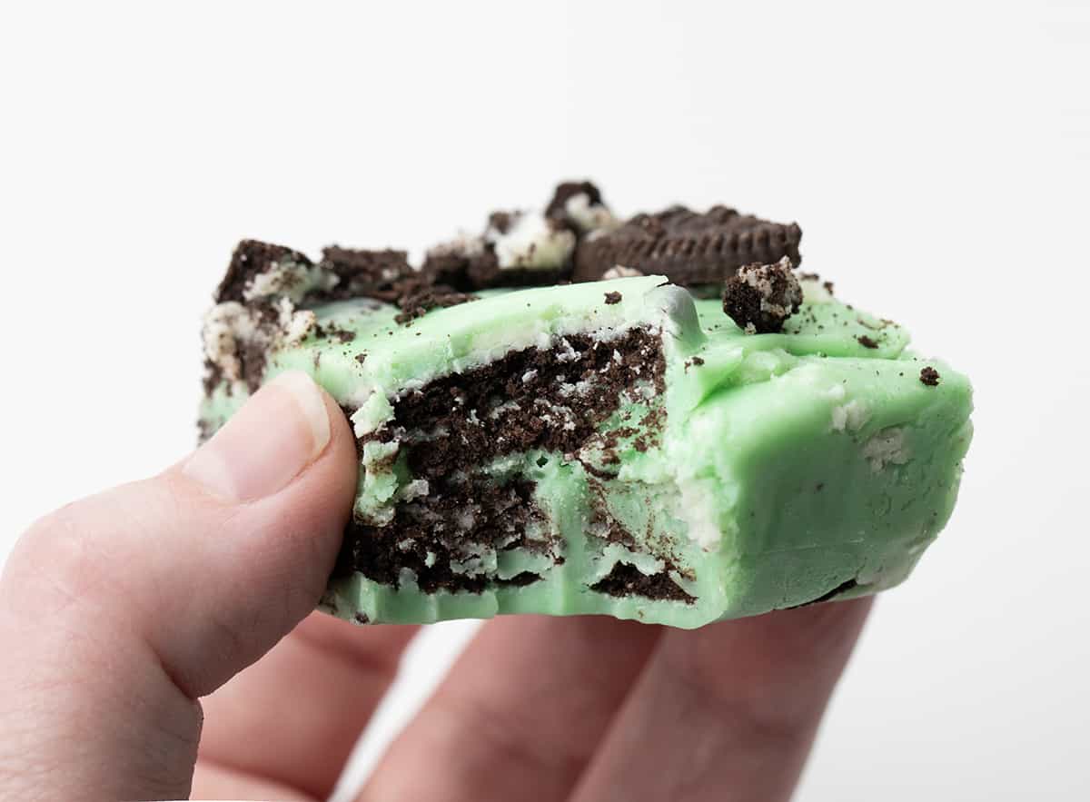 Hand Holding a Piece of Mint Oreo Fudge with a Bite Taken Out.