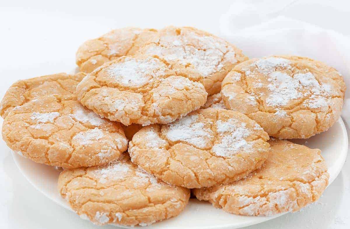 Plate of Orange Creamsicle Cookies Stacked and Confectioners Sugar Around
