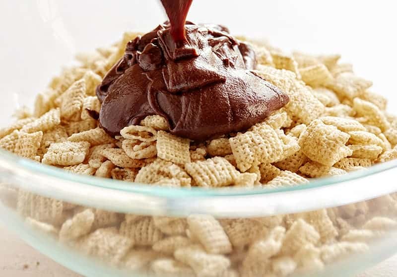 Pouring in the chocolate and peanut butter mixture for the Brownie Puppy Chow