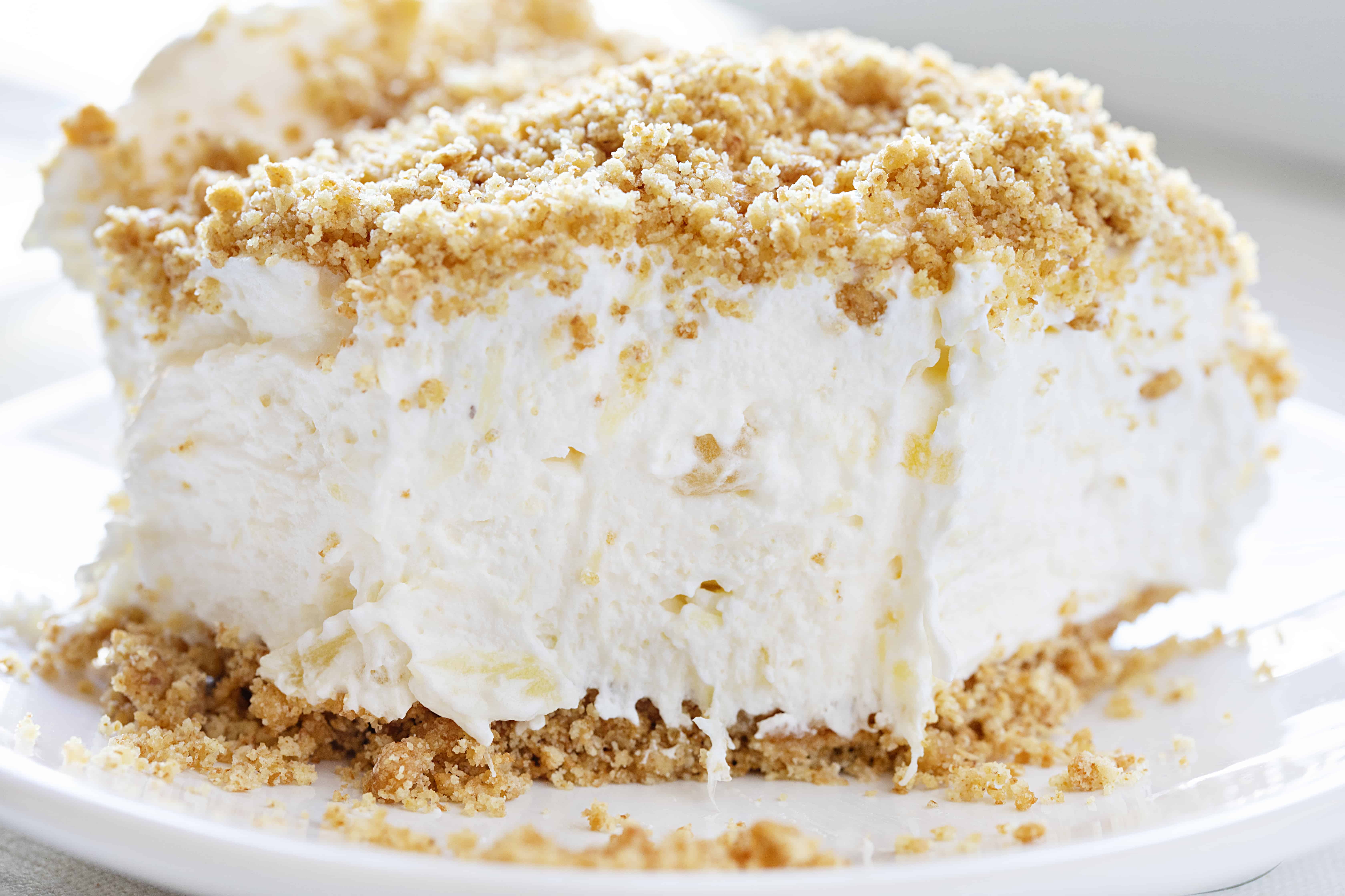 Very close up of a Pineapple Dessert on a plate showing fluffy filling and a graham cracker topping and crust.