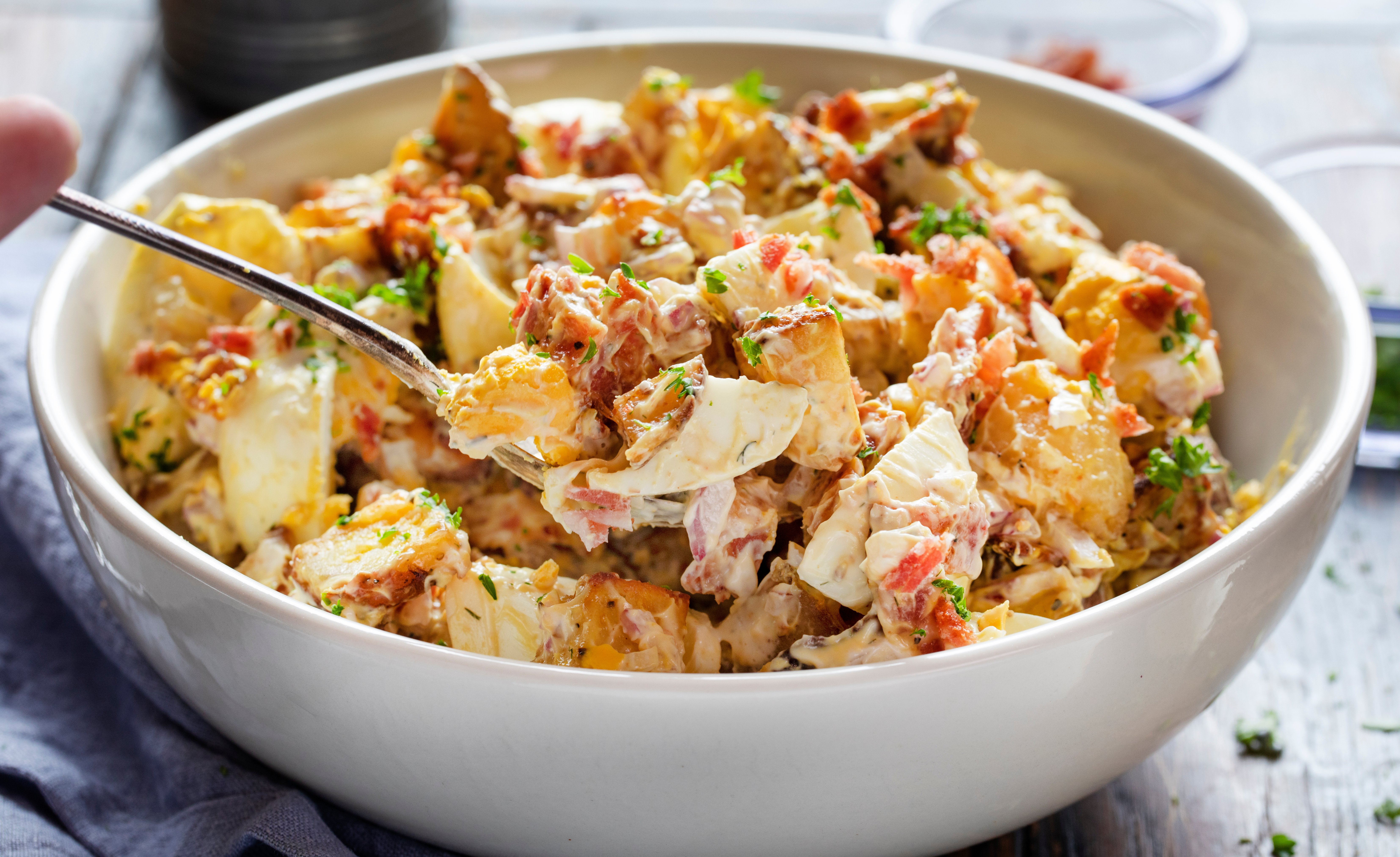 Roasted Potato Salad on a Spoon in Front of the Serving Bowl. 