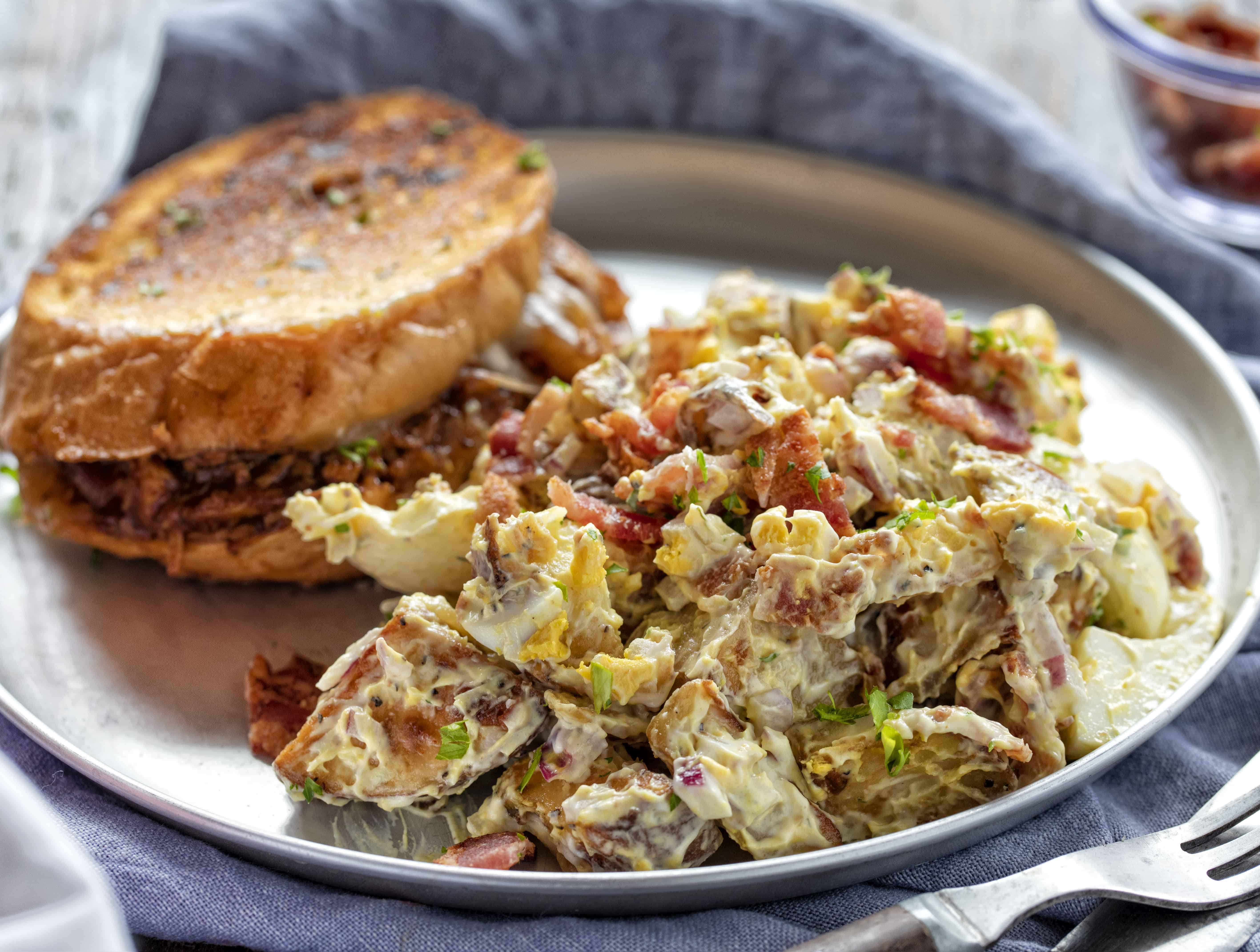 Roasted Potato Salad on a Plate Next to a Sandwich. 