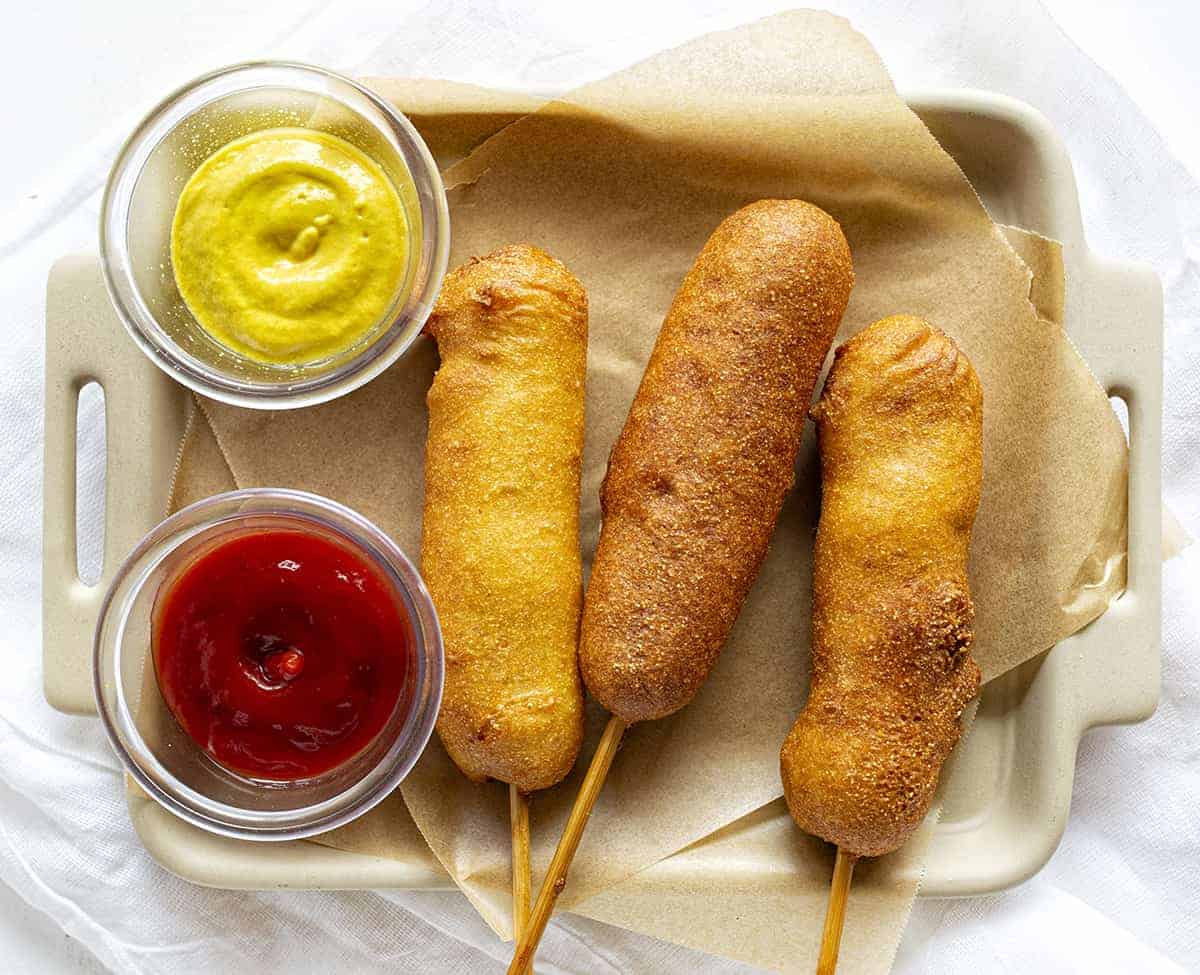 Overhead of three pronto pups with a side and mustard and a side of ketchup.