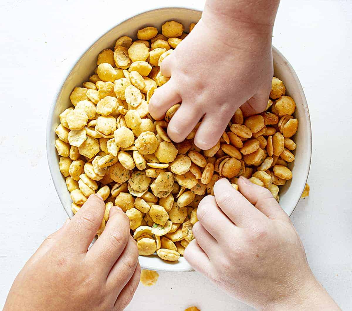 hands in bowl of seasoned oyster crackers