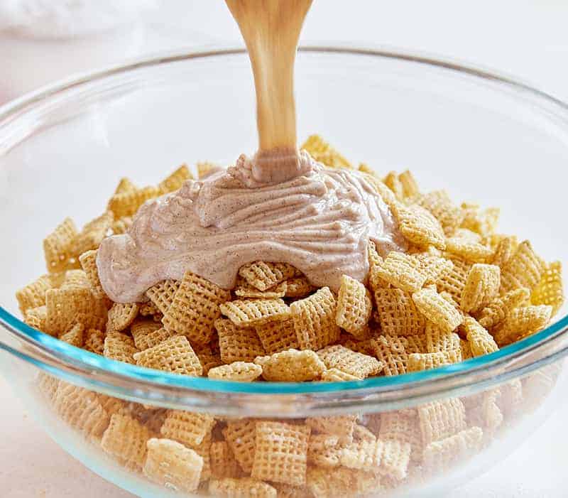 Pouring on the almond bark mixture to make Snickerdoodle Puppy Chow