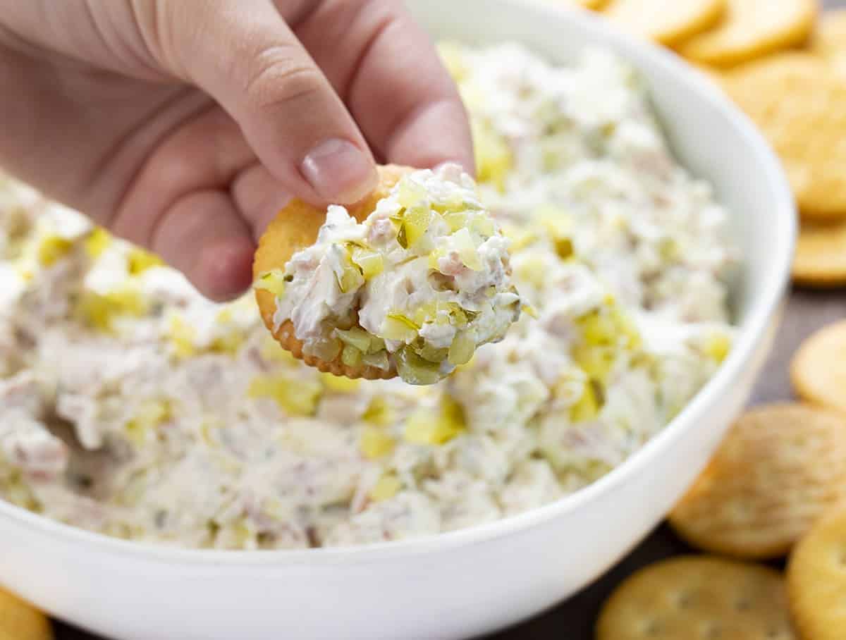 Dill Pickle Dip Being Picked up by hand holding a Ritz