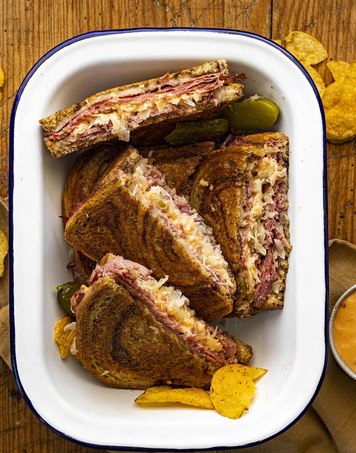 Reuben Sandwiches Cut up and In a Dish with Chips and Sauce