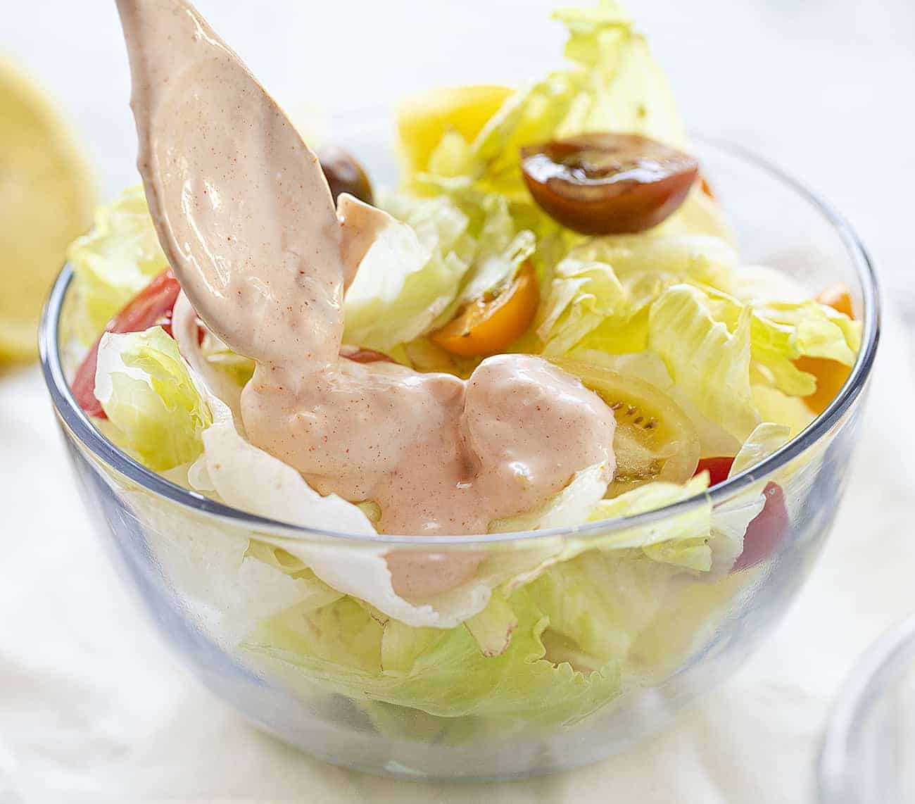 Pouring Homemade Russian Dressing on a lettuce salad