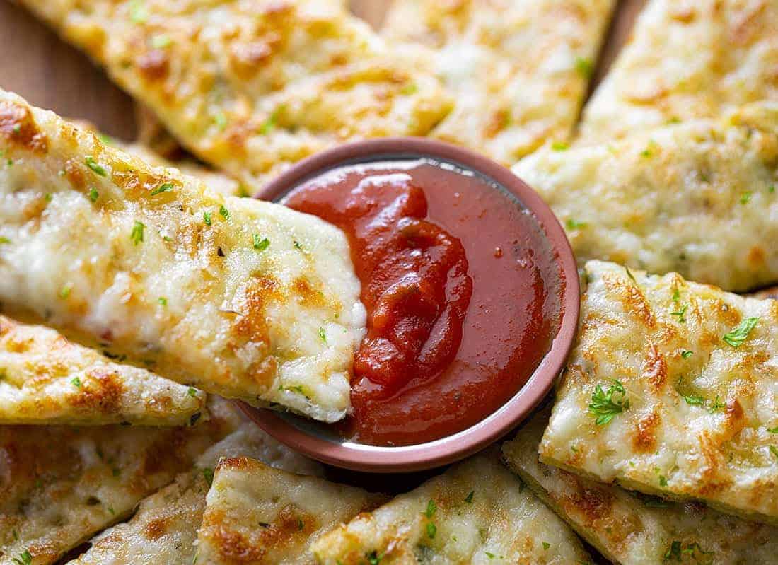 Cheesy Zucchini Breadsticks Being Dipped in Marinara