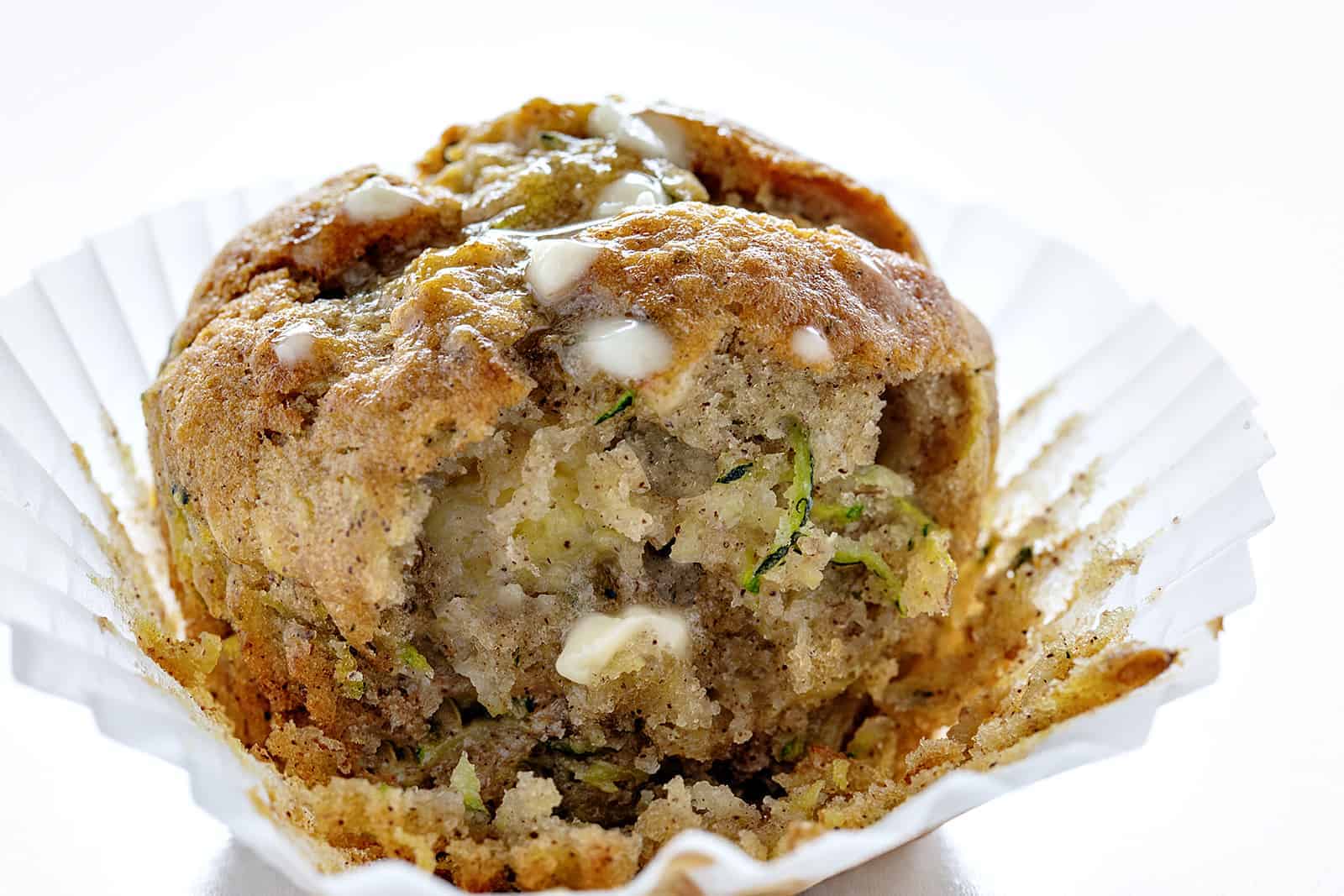 Banana Zucchini Muffin with Melted Butter And A Bite Taken Out on a Cupcake Liner.