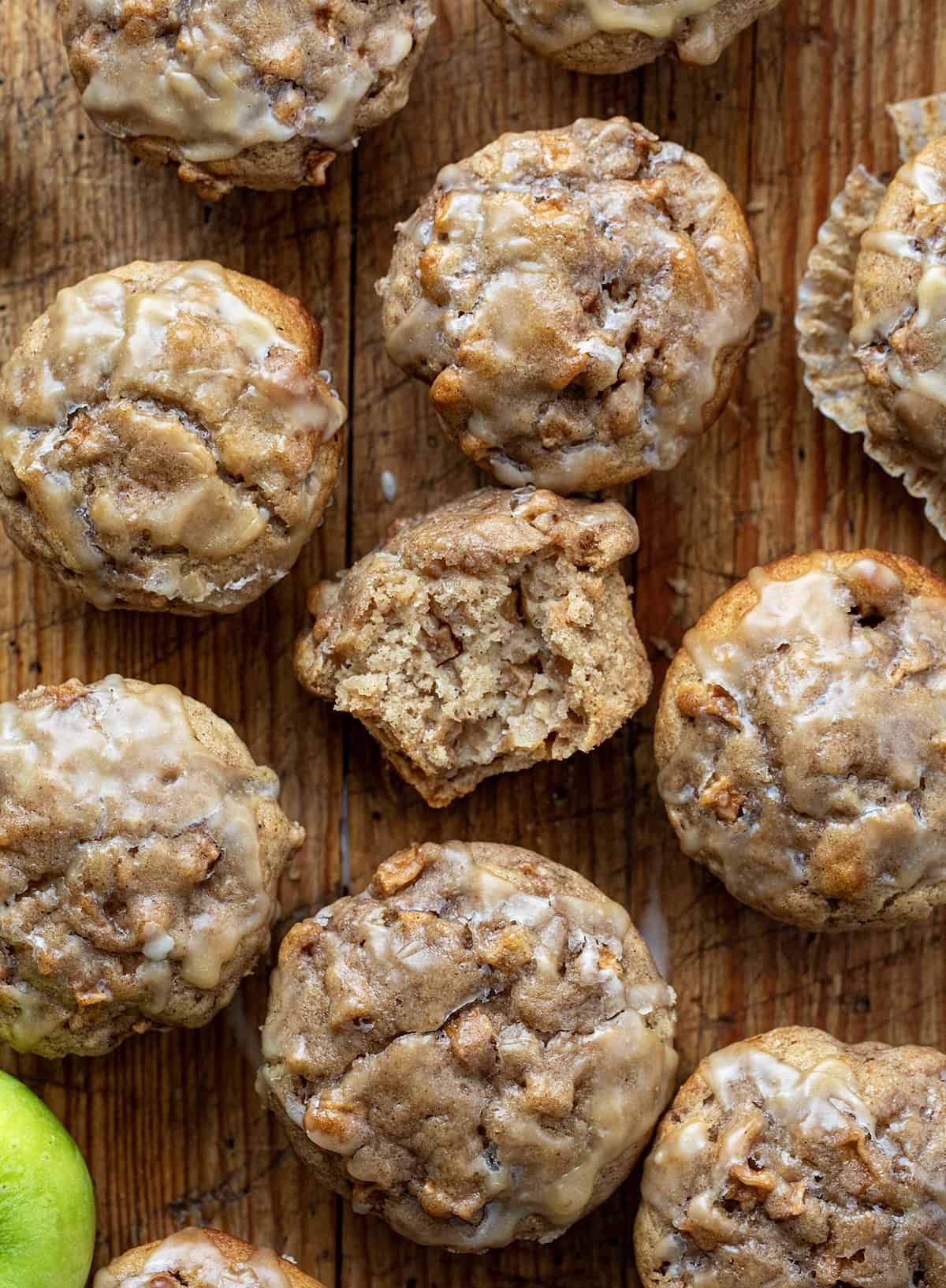 Apples Muffins on a Wooden Cutting Board with One Muffin Halved to Show Inside from Overhead.
