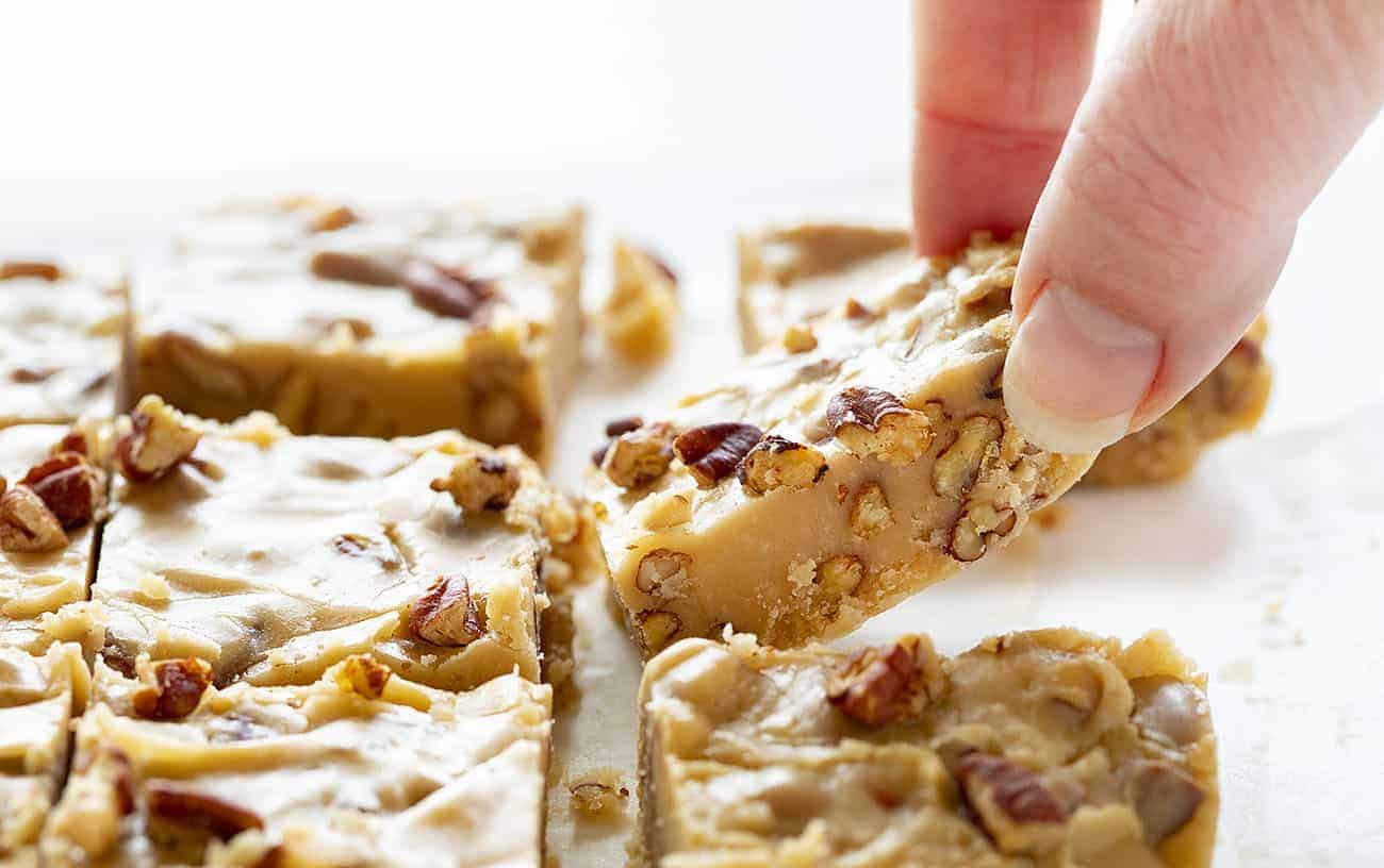 Hand picking up a piece of Butter Pecan Fudge 