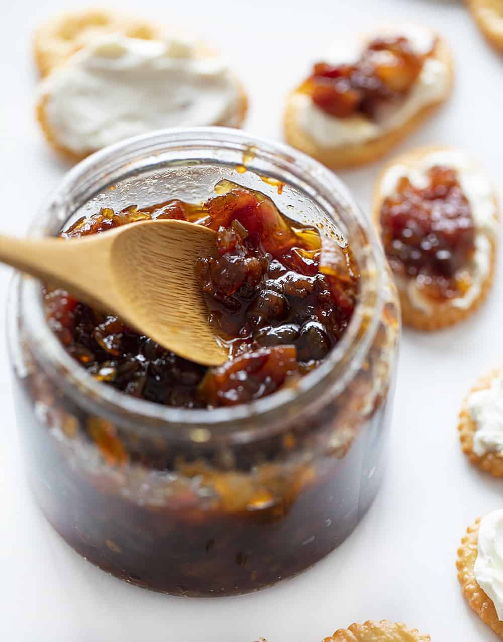 A glass jar of onion bacon jam with a wooden spoon.  jam, savory jam, onion jam, bacon jam, onion bacon jam, appetizer jam, savory jam, christmas menu, Christmas hosting, iambaker, i am baker