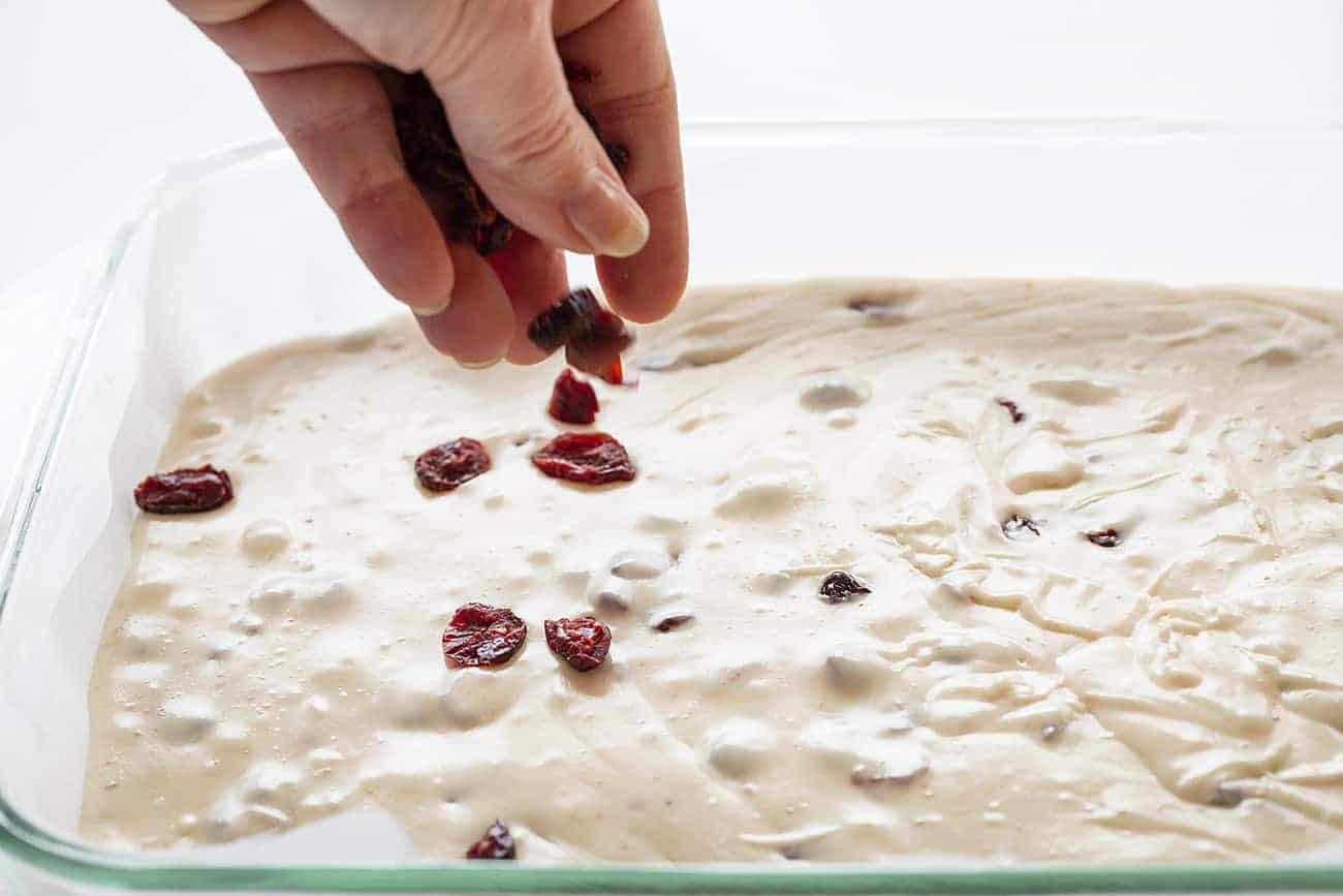 Sprinkling Craisins on White Chocolate Cranberry Fudge 