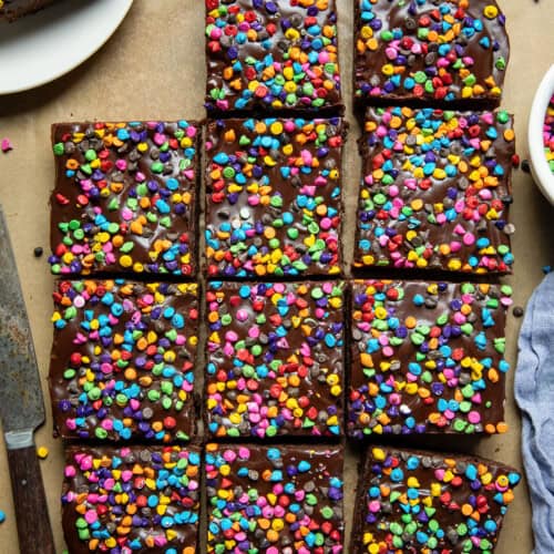 Rainbow Chip Brownies on a wooden table cut into squares with one brownie on a plate.