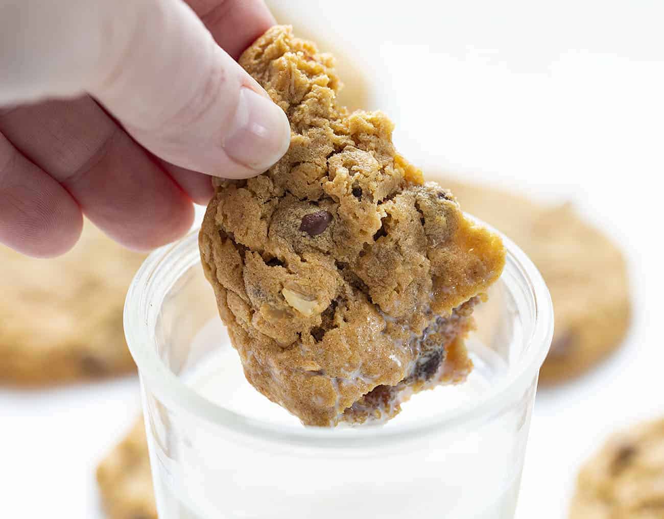 Dipping Broken Flourless Peanut Butter Chocolate Chip Cookie Into Glass of Milk