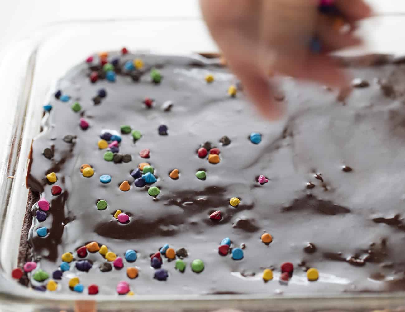 Sprinkling Rainbow Chips over Chocolate Ganache on Brownies