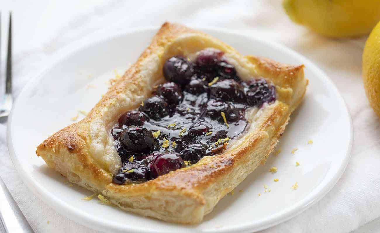 Lemon Blueberry Danish on a White Plate with Lemons