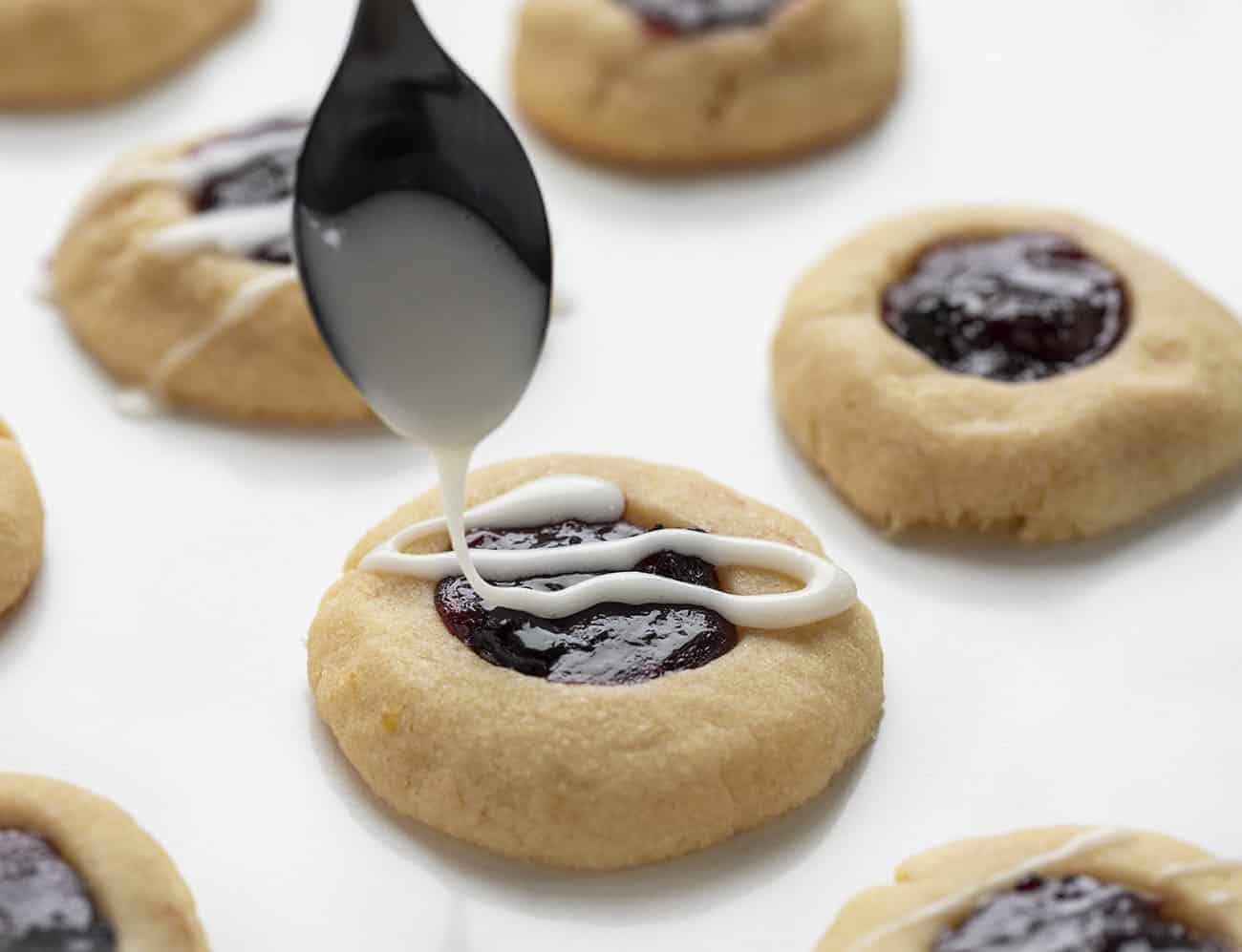 Spoon Drizzling Glaze over Lemon Blueberry Thumbprint Cookie
