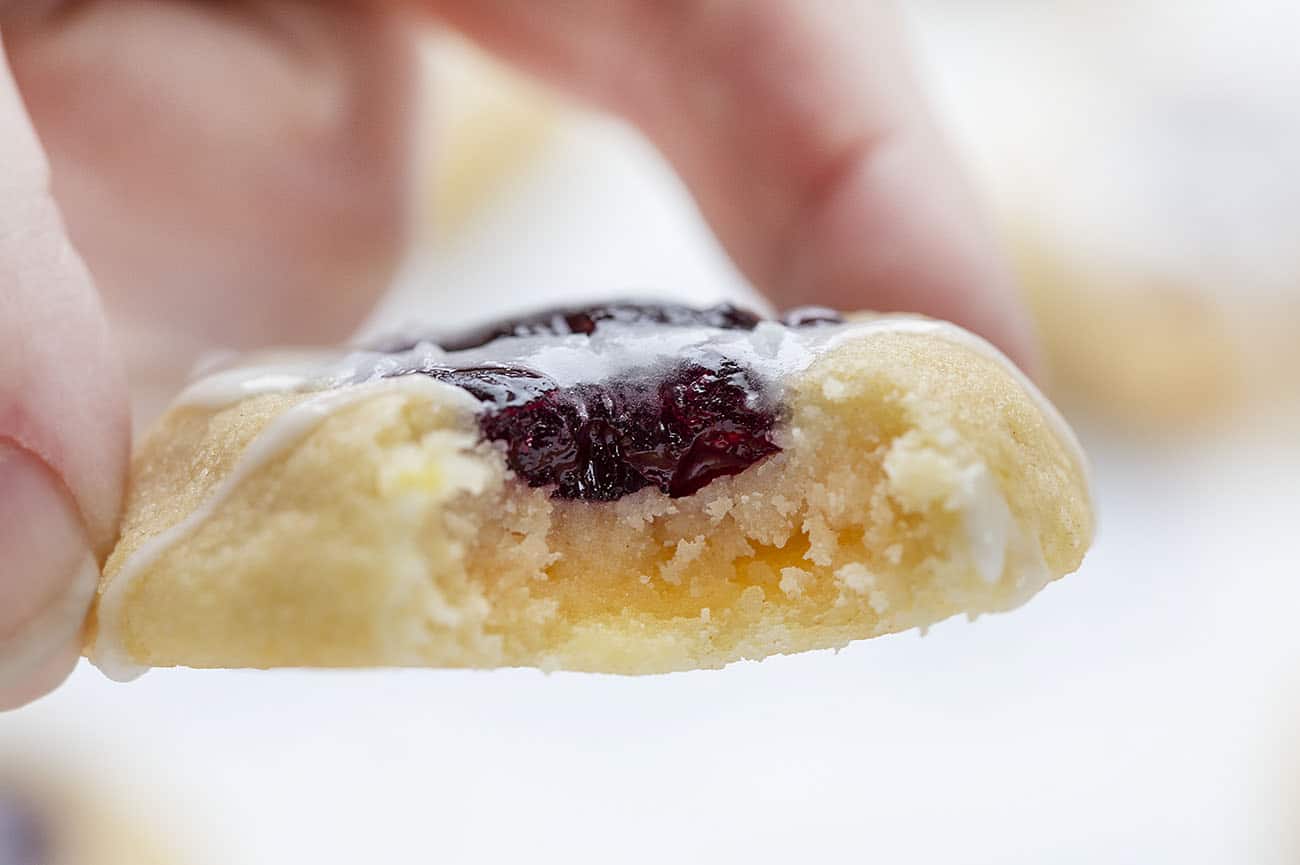 Hand holding bit into Lemon Blueberry Thumbprint Cookie