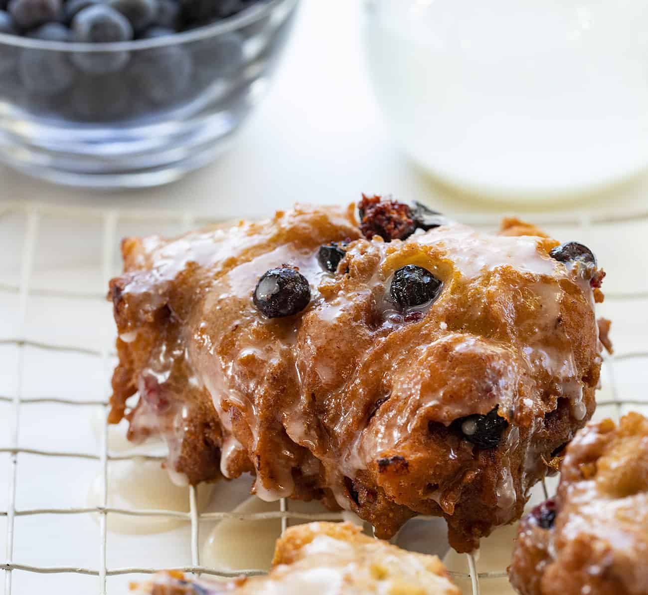 One Fresh Blueberry Fritter on Rack with Blueberries and Glaze