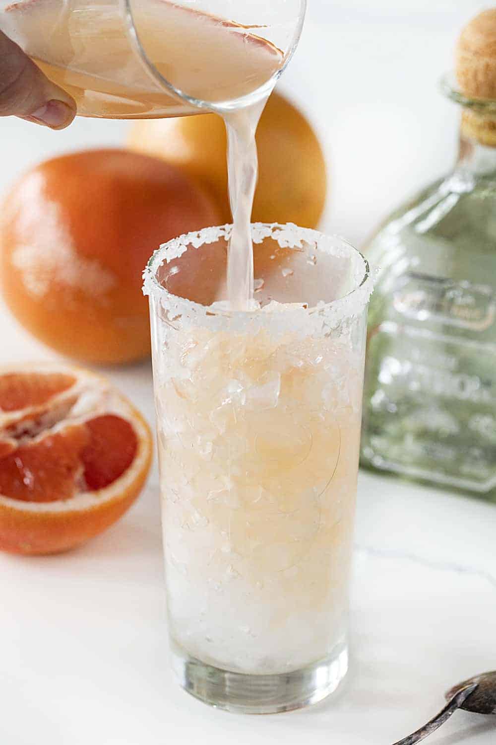 Pouring Grapefruit into tall glass making a Paloma