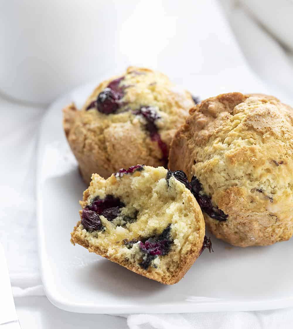  Piatto bianco con muffin ai mirtilli a lievitazione naturale e uno strappato a metà con burro