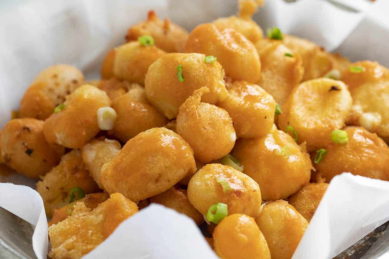 Basket of Buffalo Cheese Curds with Buffalo Sauce and Scallion Sprinkled on Top