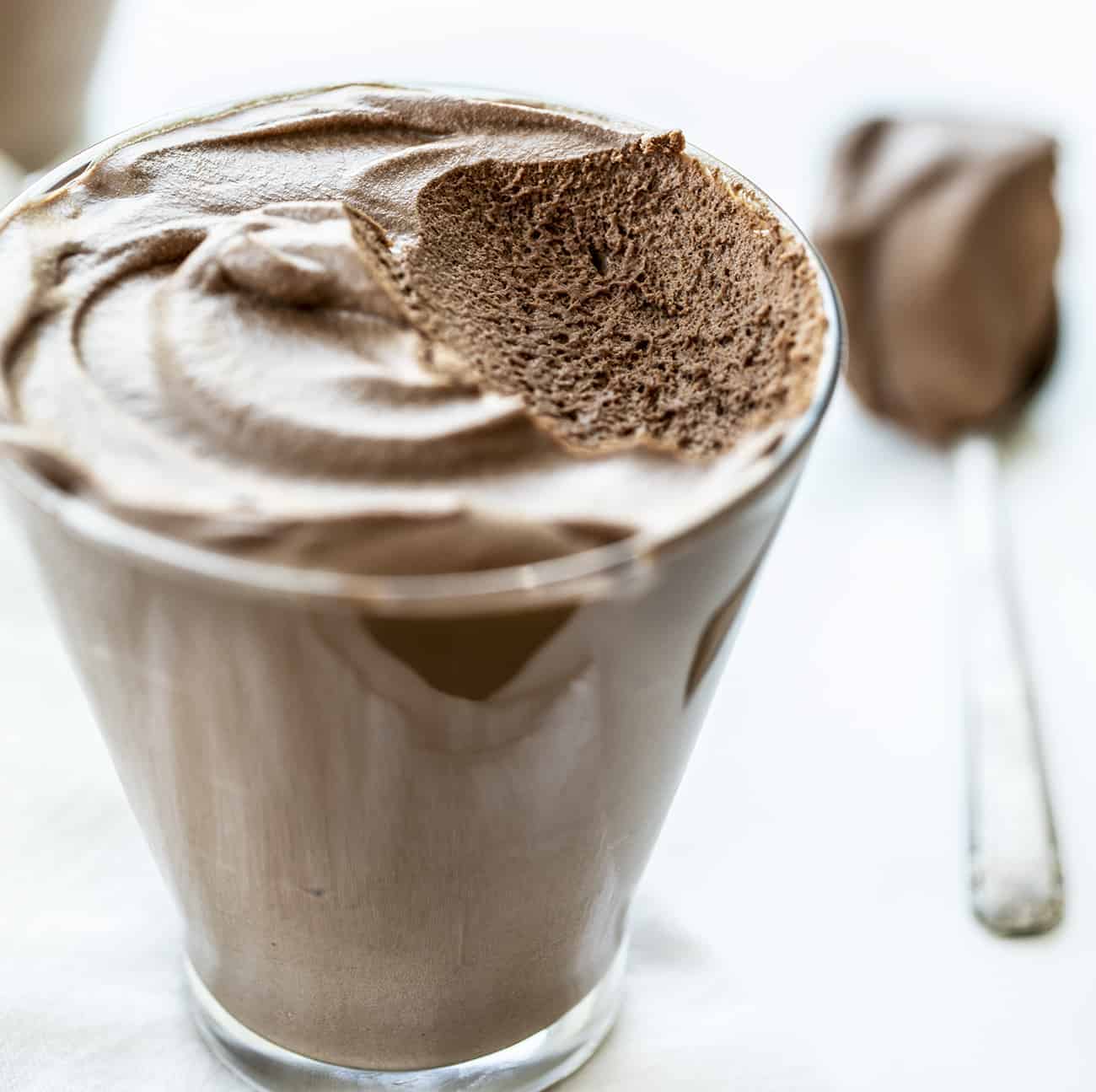 Cup of Easy Chocolate Mousse with Some removed on the Spoon Next to It