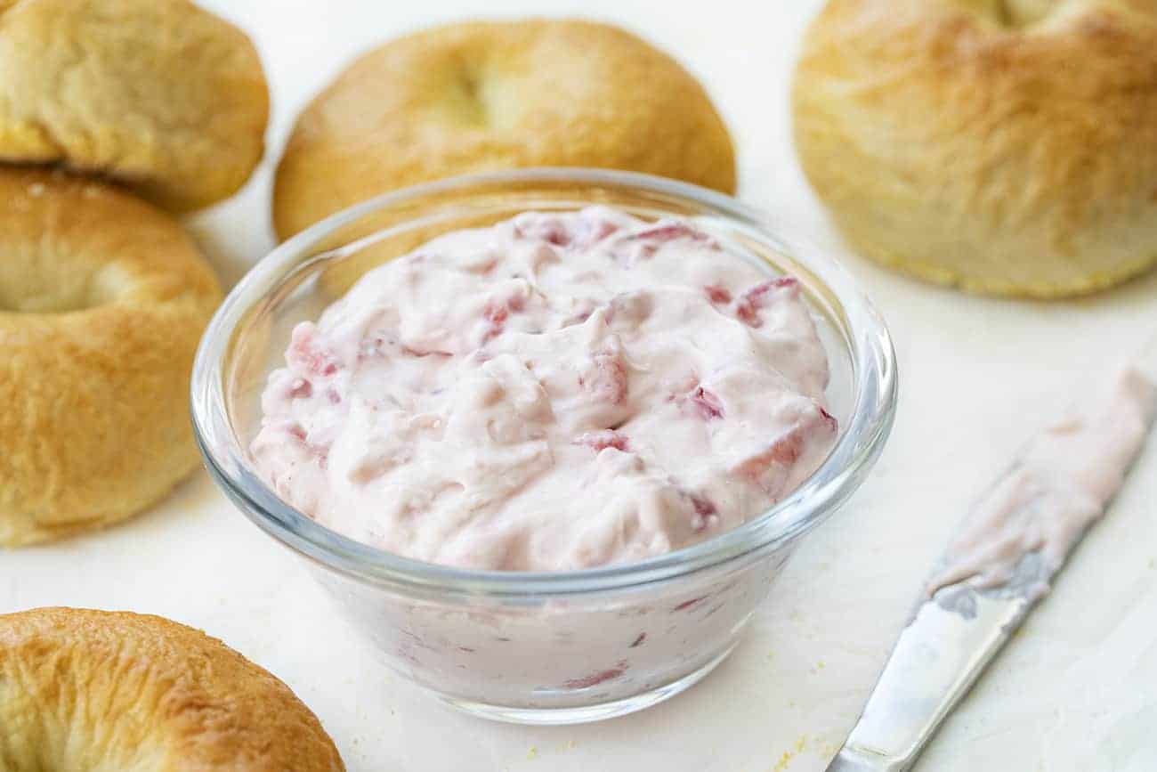 Bowl of Homemade Strawberry Cream Cheese Next to Plain Bagels