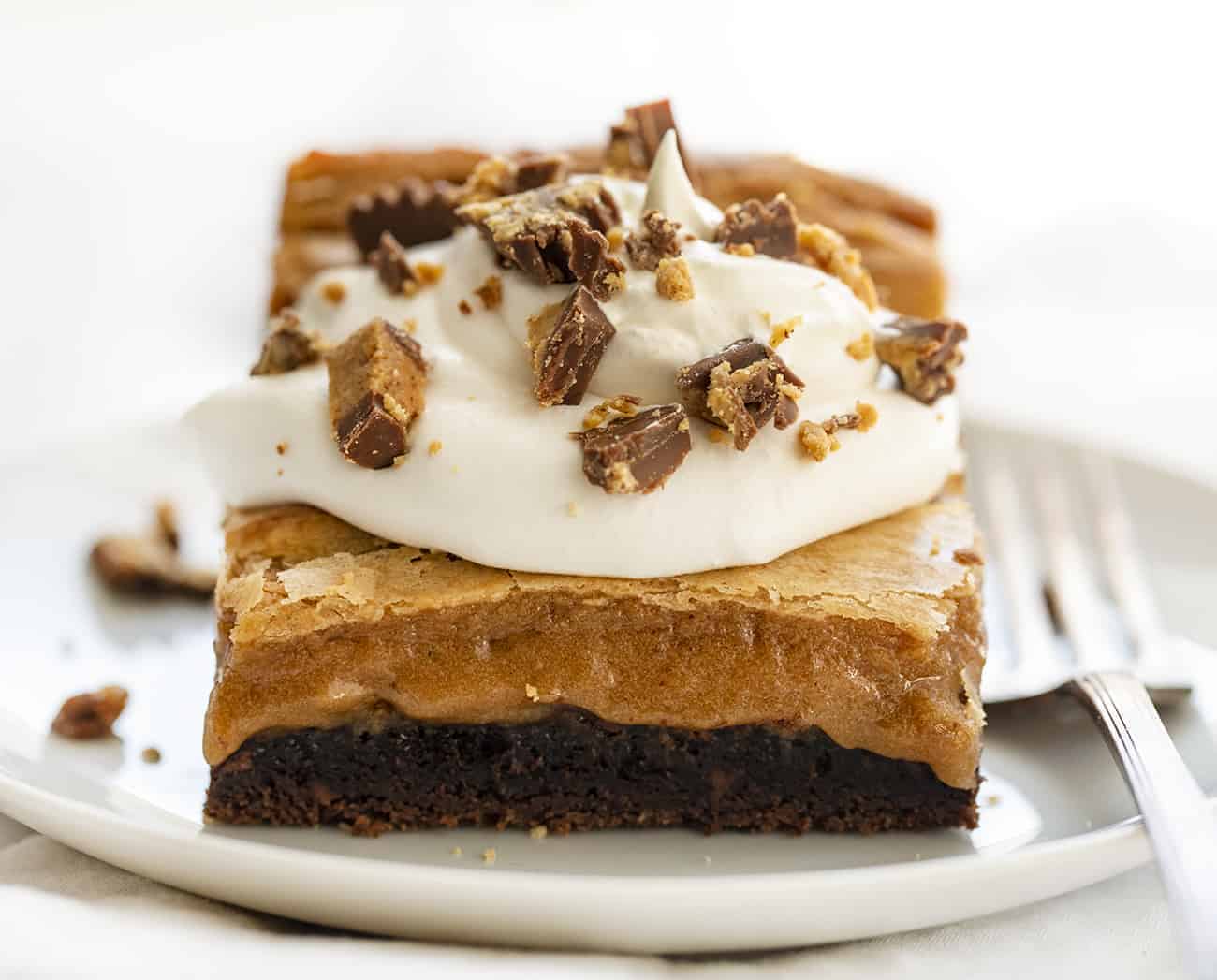 Reeses Ooey Gooey Cake Slice on a White Plate with Fork Next to It
