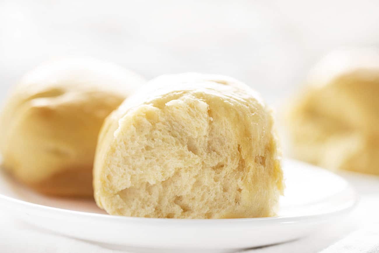 Hawaiian Dinner Rolls on White Plate with Rolls in Background