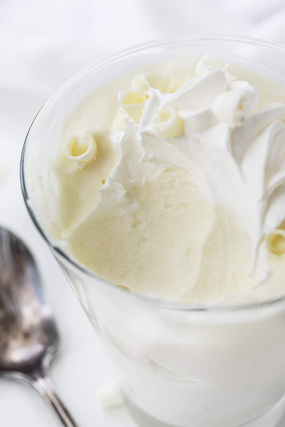 Glass of White Chocolate Mousse with Some Removed and Spoon Next to Glass