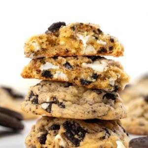 Stack of Cookies and Cream Cookies with the top cookie broken in half showing the tender inside texture.