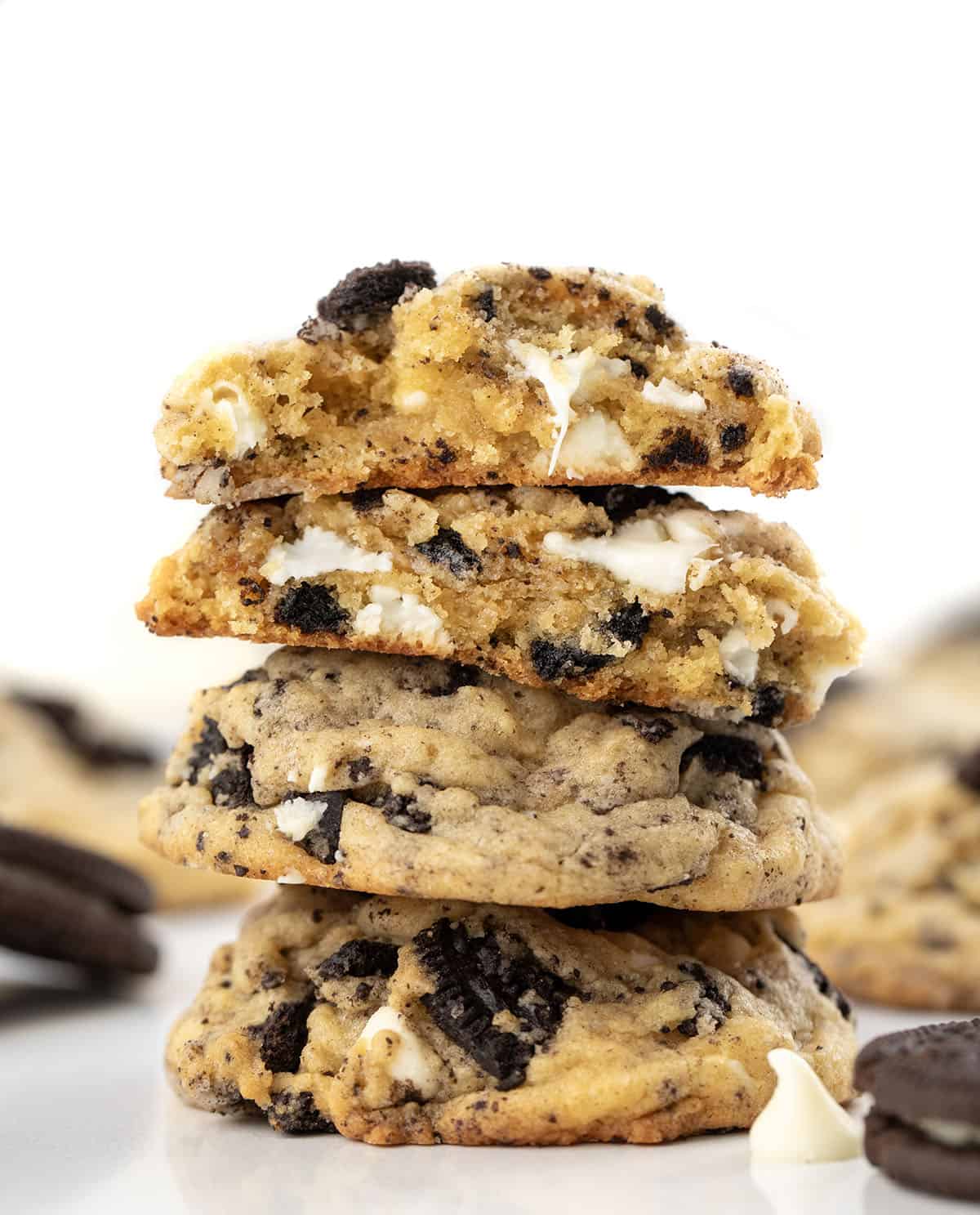 Stack of Cookies and Cream Cookies with the top cookie broken in half showing the tender inside texture.