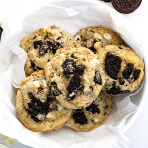 Bowl of Cookies and Cream Cookies on a white table with Oreos and milk.