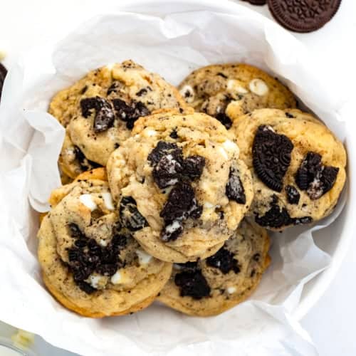 Bowl of Cookies and Cream Cookies on a white table with Oreos and milk.