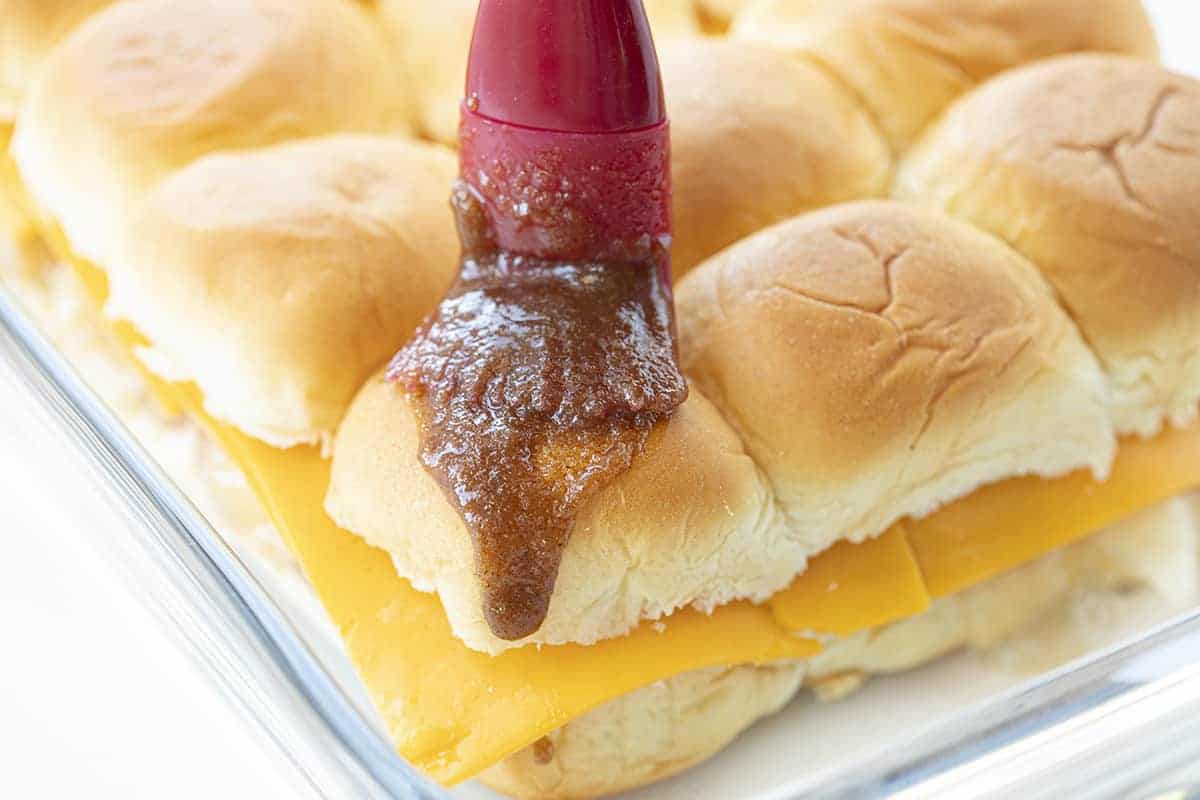 Drizzling Sauce over Apple Cheddar Sliders Before They Are Baked