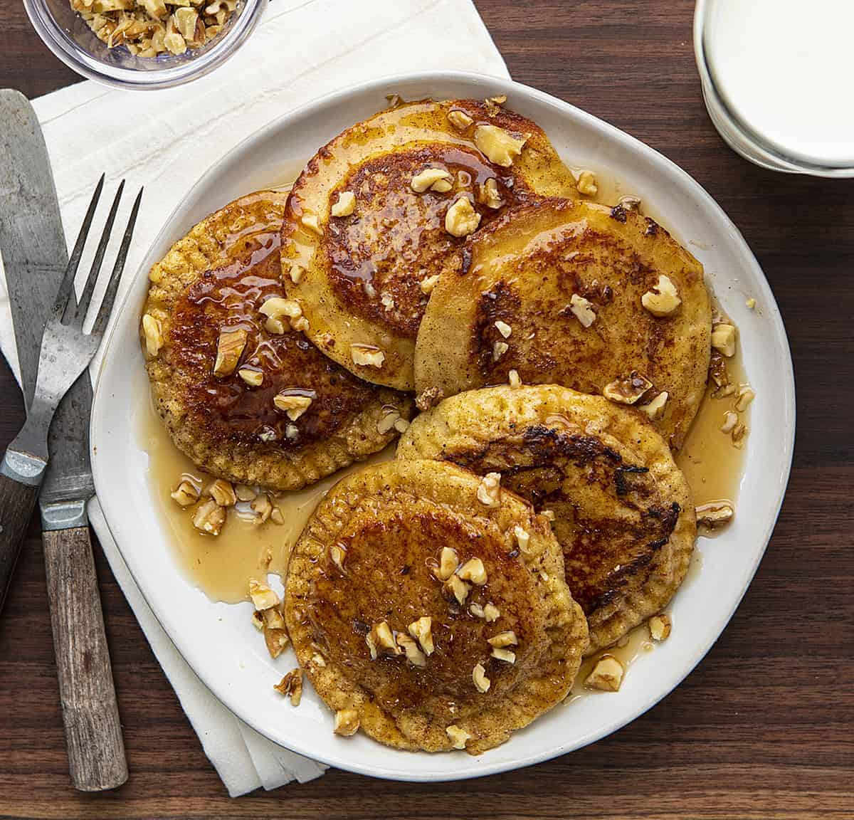 Overhead Image of Banana Bread French Toast Pockets on a Plate on Dark Cutting Board with Milk and Nuts