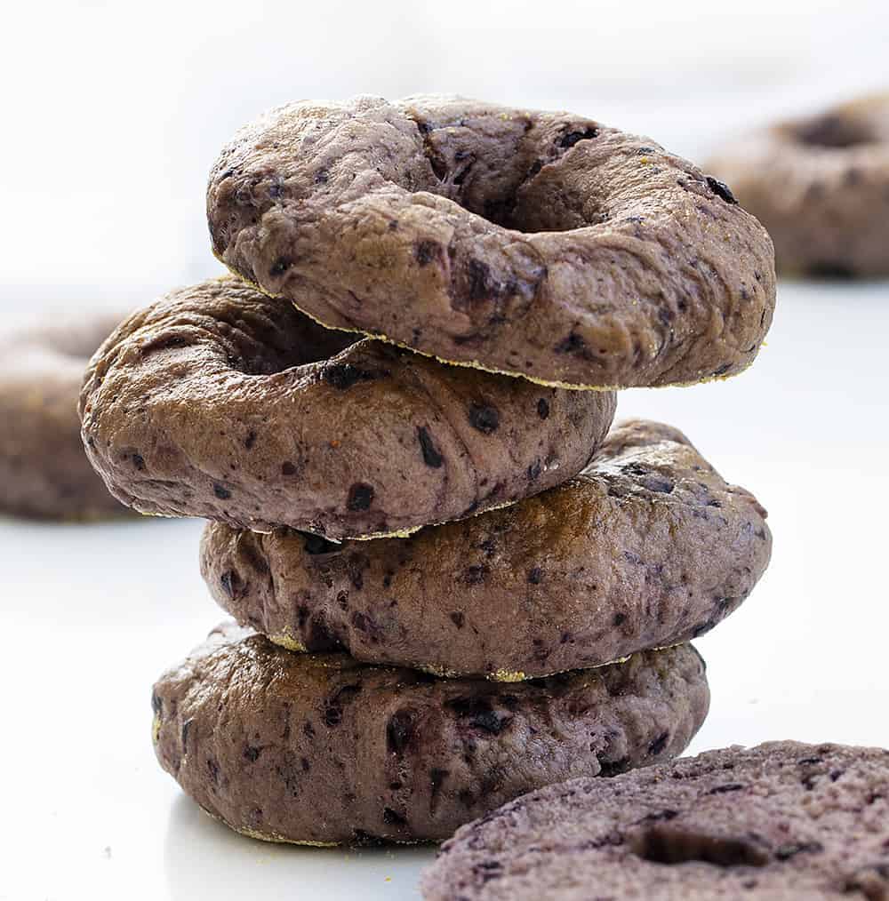 The Best Blueberry Bagels Recipe Stacked on Top of Each Other with A Cut Bagel Laying Next to It